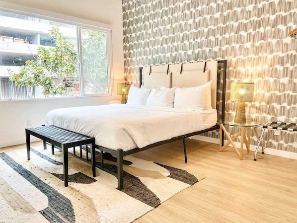 A bedroom with a bed, a small table, a lamp, and a patterned wall. - Stylish San Diego Apt | Gaslamp at Your Door (San Diego)