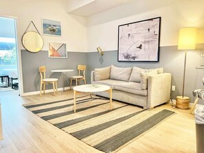 A modern living room with a sofa, coffee table, and chairs, a striped rug, and artwork on the walls. - Stylish San Diego Apt | Gaslamp at Your Door (San Diego)