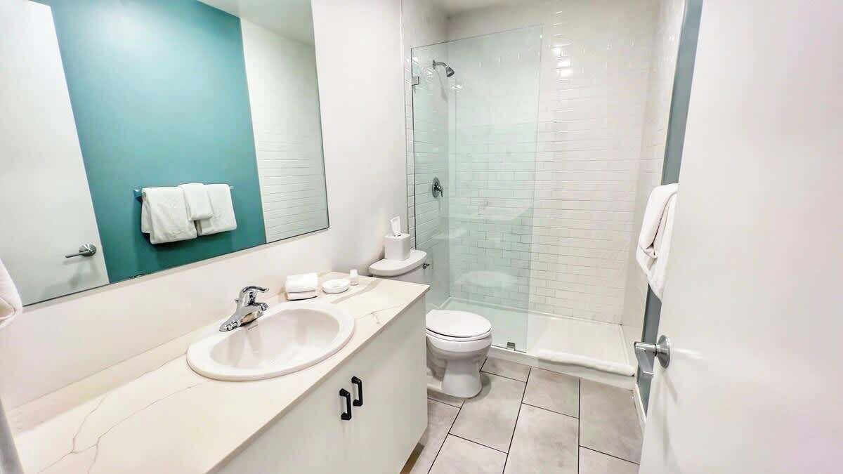 A modern bathroom with a sink, toilet, and glass-enclosed shower.
