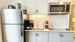 Eine Küche mit einem Edelstahl-Kühlschrank, einer Mikrowelle und einem Spülbecken.