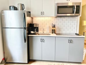 A kitchen with a stainless steel refrigerator, a microwave, and a sink. - Bars, Eats & Nightlife | Central San Diego King Apt (San Diego)