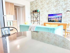 Ein modernes Wohnzimmer mit Esstisch, Fernseher und Wand mit Muster.