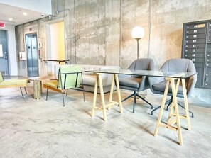 Ein moderner Konferenzraum mit Glastisch, zwei Stühlen, einer Bank und einem wandmontierten Schrank.