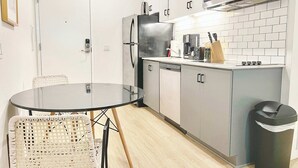 Una cocina compacta equipada con microondas, refrigerador y un pequeño comedor con una mesa redonda y sillas de mimbre.