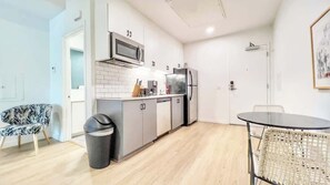 Una cucina funzionale con microonde, frigorifero e lavello. C'è un'area pranzo con tavolo e sedie.