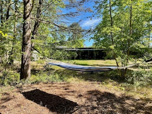 A hammock tied between trees in a wooded area with a building in the background. - 4 Star Holiday Home in Vaeggerlose (Vaeggerlose)