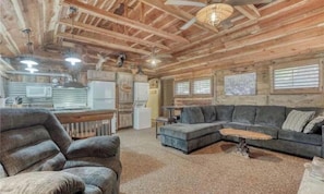 A log cabin interior with a living room, kitchen, and dining area.