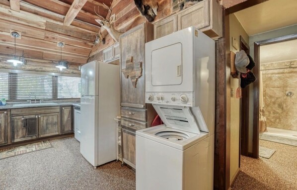 A kitchen with a refrigerator, washing machine, and wooden cabinets.