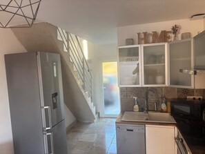 Eine Küche mit einem Edelstahl-Kühlschrank, einer Spülmaschine, einer Mikrowelle und Schränken mit Milchglasfronten.