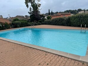 Ein rechteckiger Pool mit klar blauem Wasser, umgeben von einem Pflasterweg.