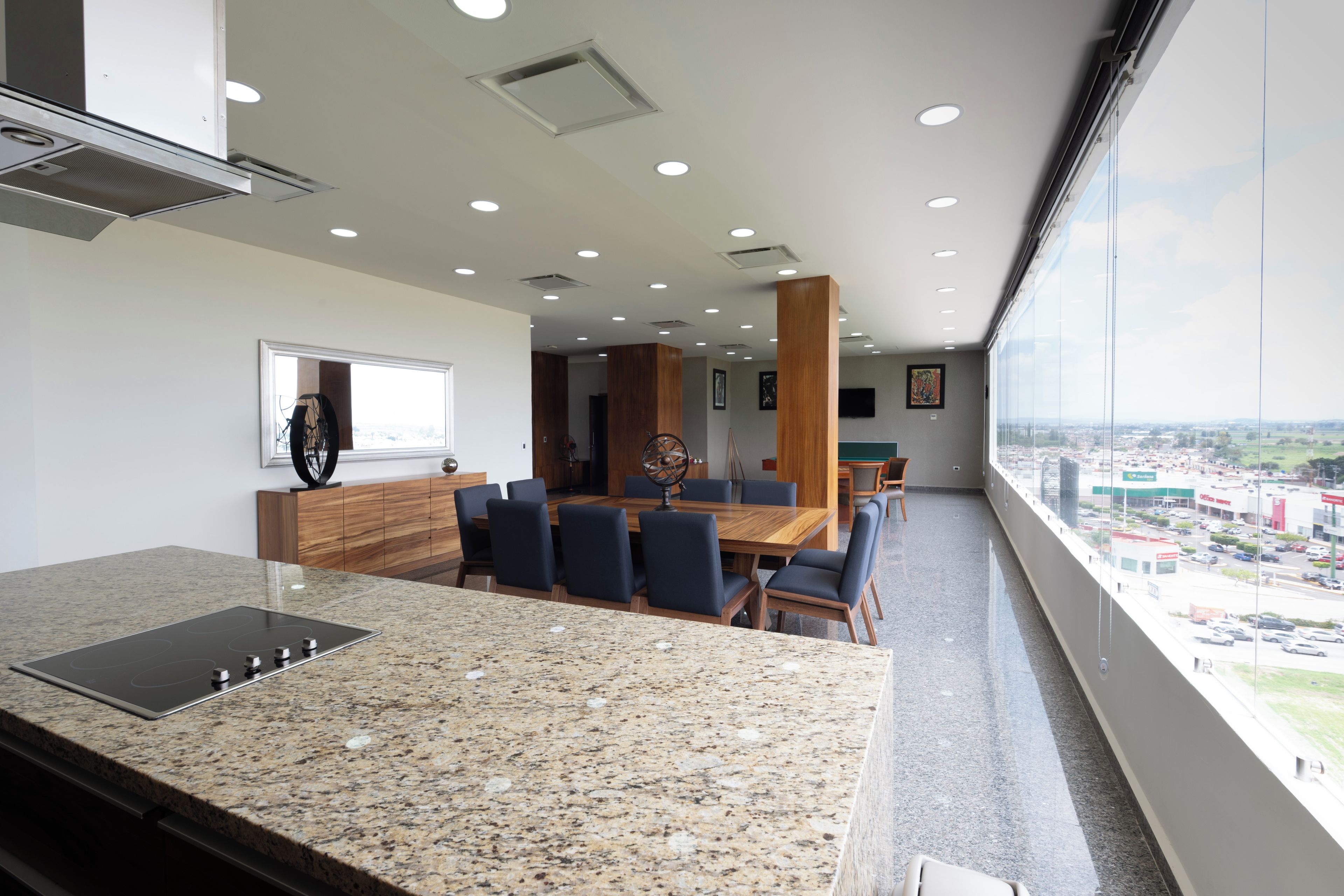 Una cocina moderna con encimeras de granito y un comedor con mesa y sillas de madera.