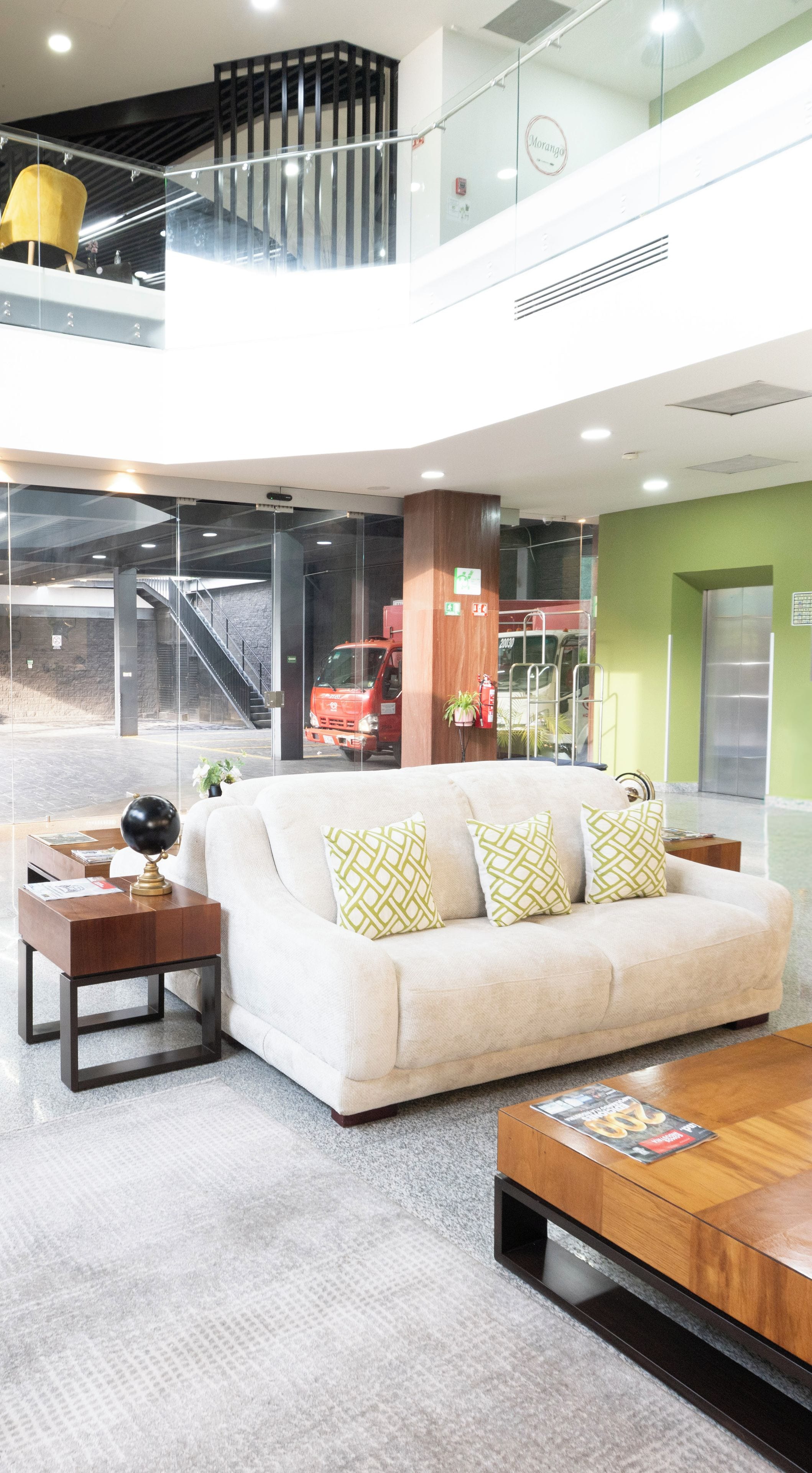 A modern lobby with a sofa, coffee table, and a glass railing.