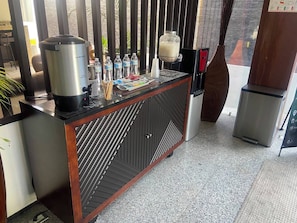 A bar area with a coffee machine, water bottles, and a milk dispenser. - Hoteles EJM Premium (Irapuato)