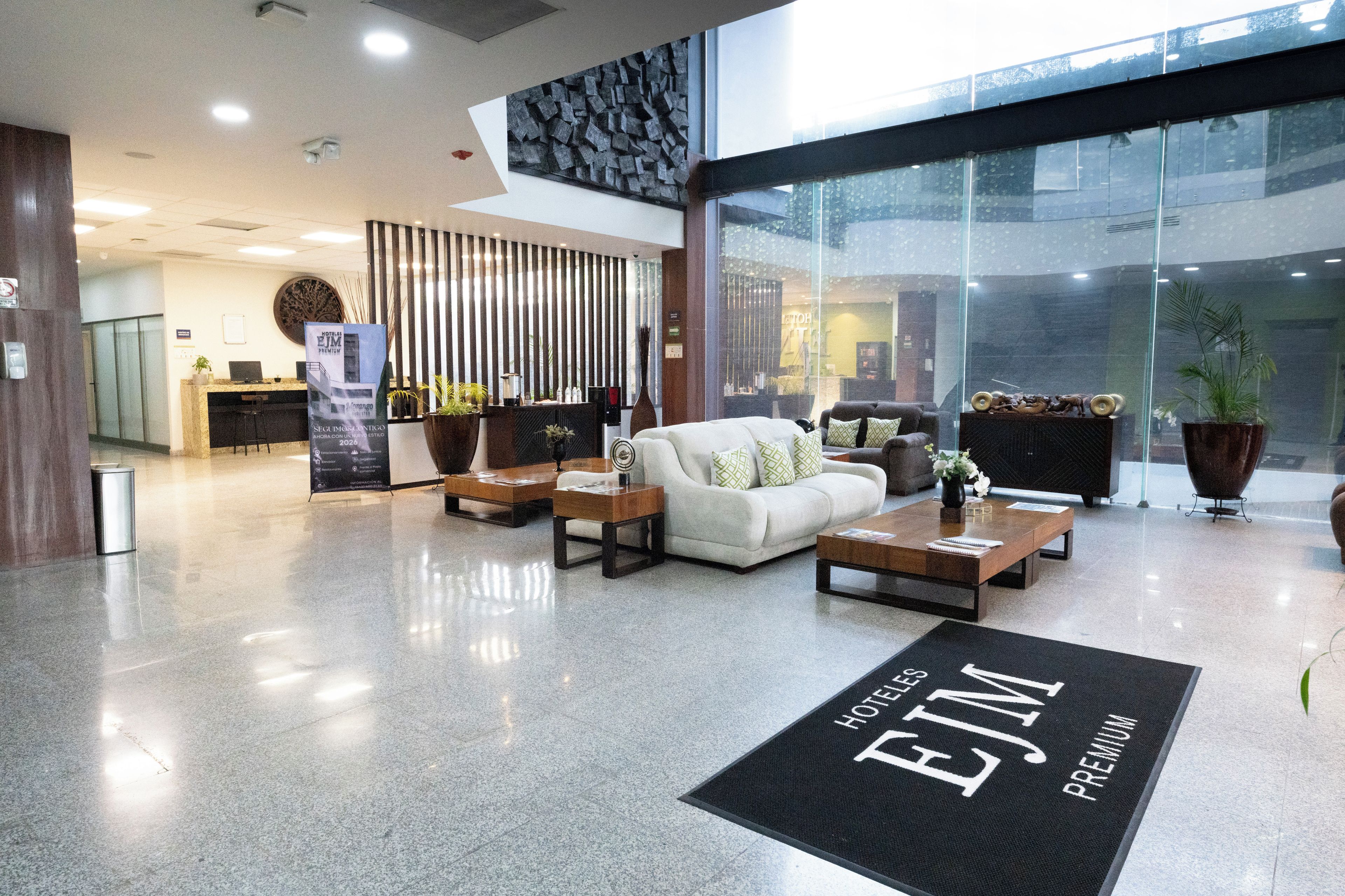 Un vestíbulo de hotel con mostrador de recepción, zona de estar y un amplio ventanal.