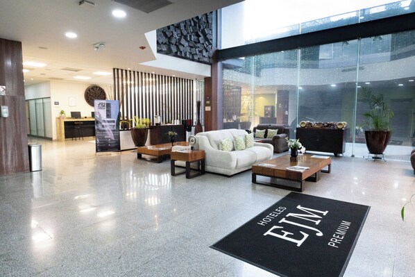 Un hall d’hôtel comprenant un comptoir d’accueil, un espace salon et une grande baie vitrée.
