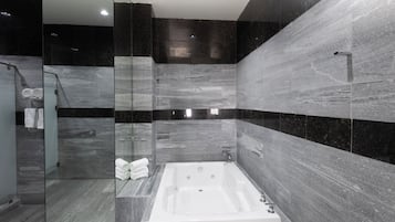 Un baño moderno con una bañera independiente, cabina de ducha con mampara de vidrio y paredes de mármol.