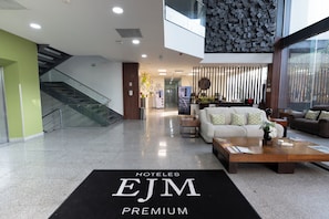 A hotel lobby with a reception desk, seating area, and a staircase. - Hoteles EJM Premium (Irapuato)