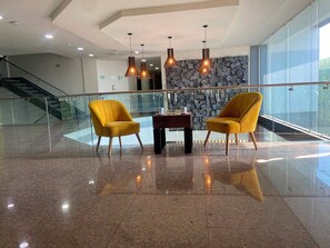 Un hall d’entrée avec deux fauteuils jaunes, une petite table et un mur en pierre.