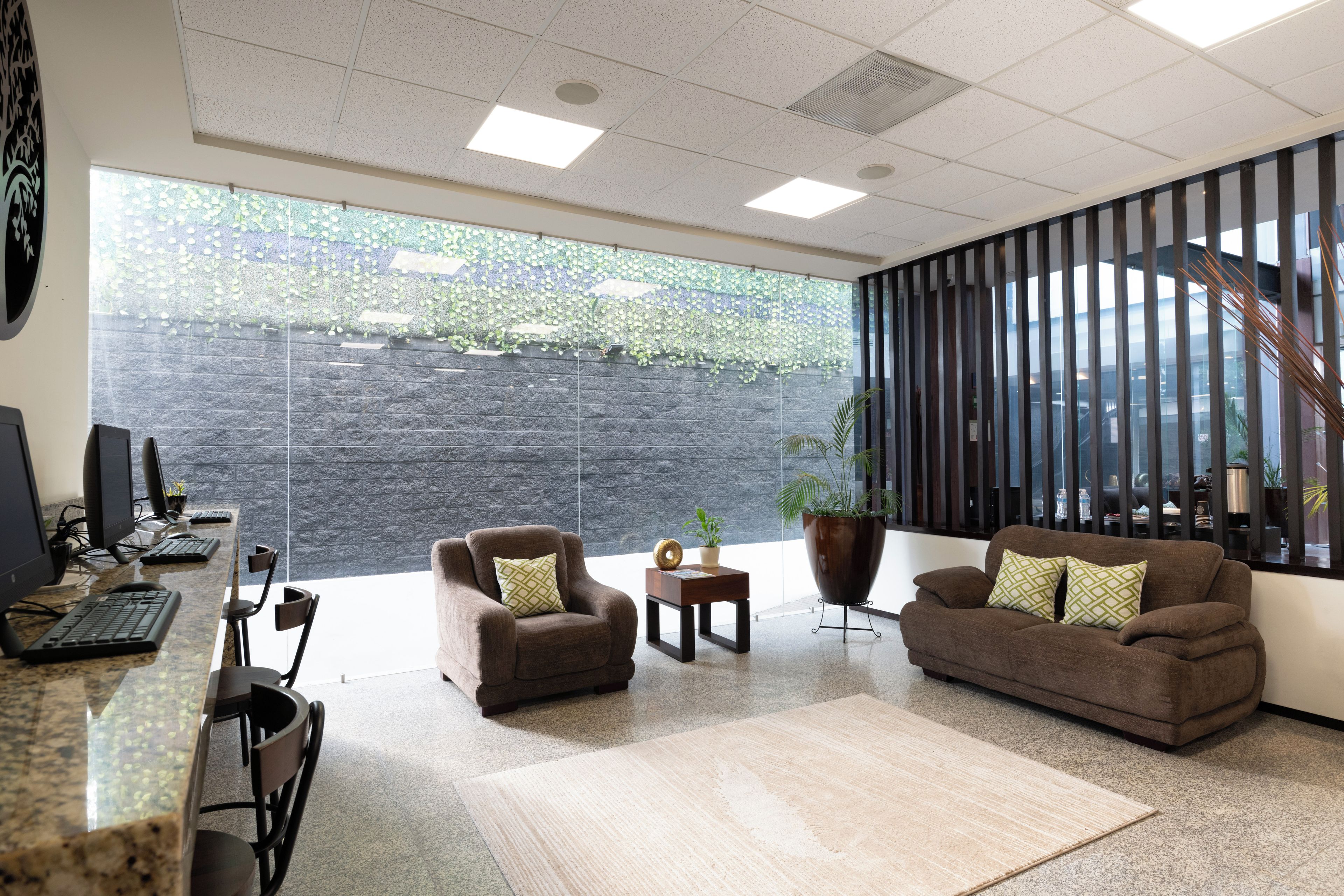 A modern office space with a reception area, seating, and a large window with a view of greenery.
