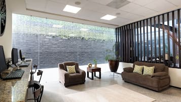 A modern office space with a reception area, seating, and a large window with a view of greenery.