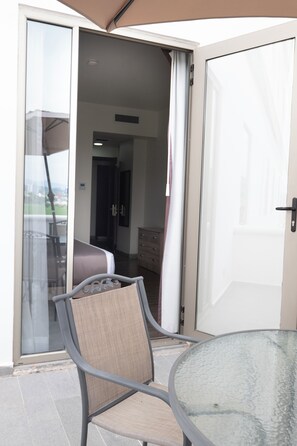 A room with a sliding glass door leading to a balcony, a bed, a dresser, and a chair.