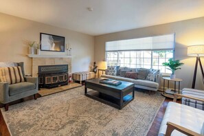 Ein Wohnzimmer mit Kamin, Sofa, Couchtisch und Lampe.