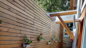 A wooden wall with potted plants, a brick pathway, and a wooden structure with a glass roof. - Morada Bem Me Quer (Canela)