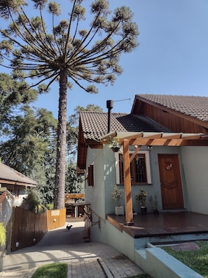 A house with a tiled roof, a wooden porch, and a large tree in the background.