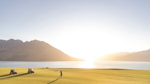 A golf course with a view of a body of water and mountains in the background.