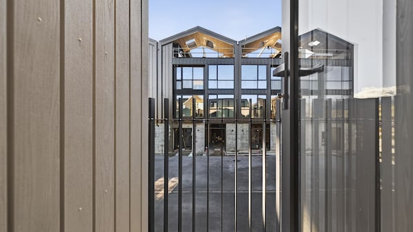 A gated entrance to a building with a modern architectural design, featuring large windows and a visible construction area.