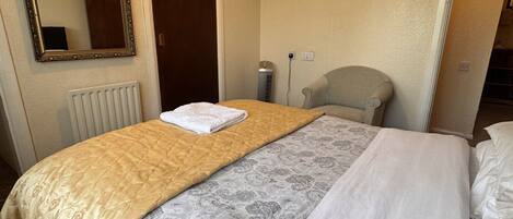 Et hotelværelse med en seng, et fjernsyn ophængt på væggen, en radiator og en dør.
