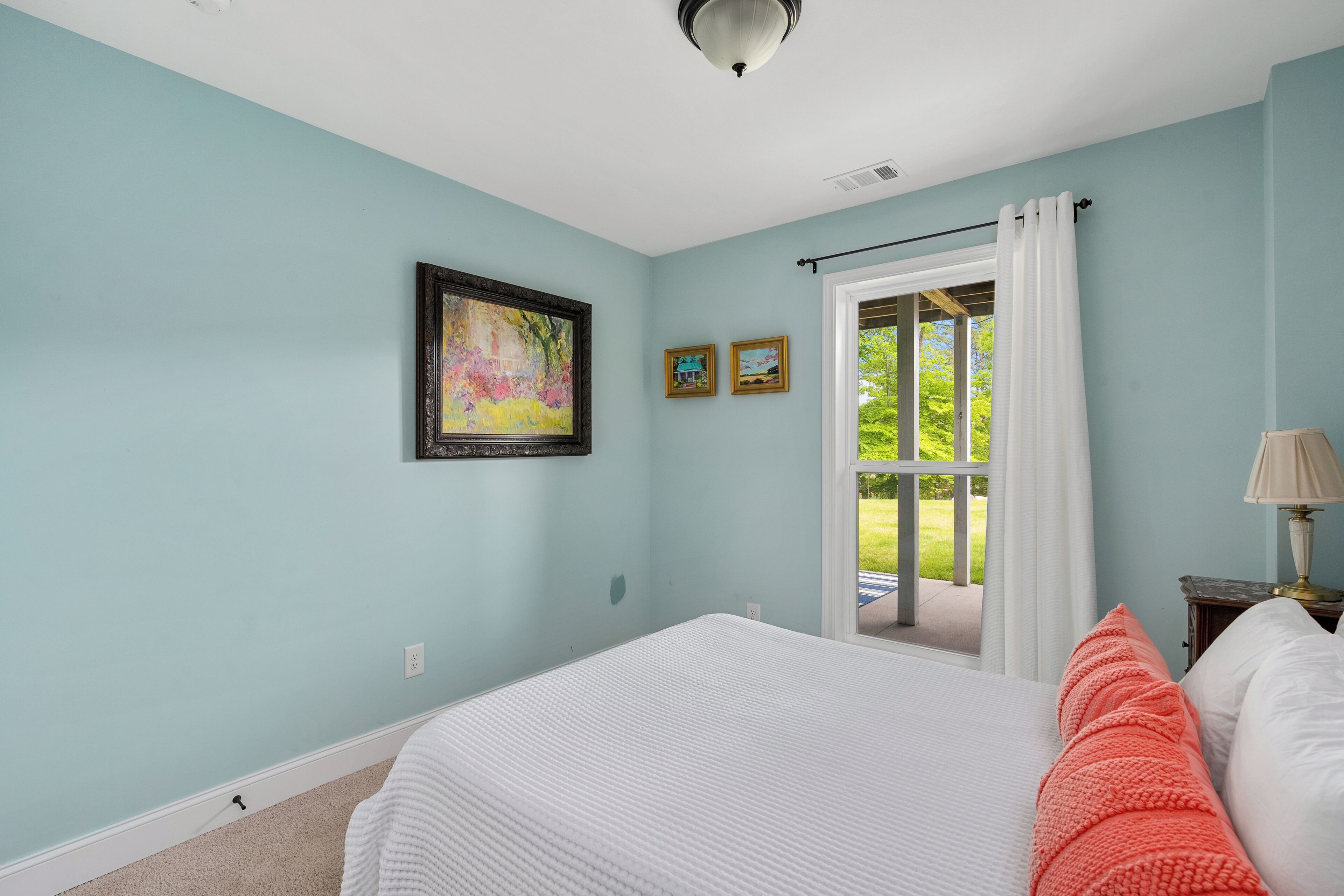 Une chambre à coucher avec un lit, une fenêtre avec des rideaux et un tableau accroché au mur.