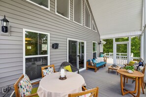 Une terrasse couverte avec une table, des chaises et un canapé.