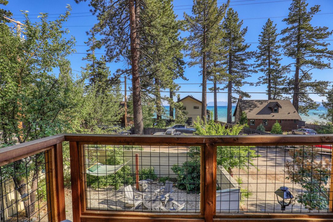 A wooden deck with a view of a beach and houses in the distance.