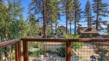A wooden deck with a view of a beach and houses in the distance.