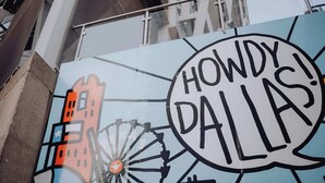 Un cartello con la scritta 'HOWDY! DALLAS!' e una stilizzazione della città.