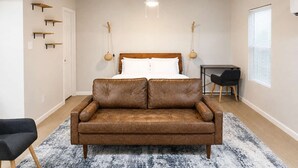 Una camera da letto con un letto, una poltrona in pelle marrone, un tavolino e una sedia.