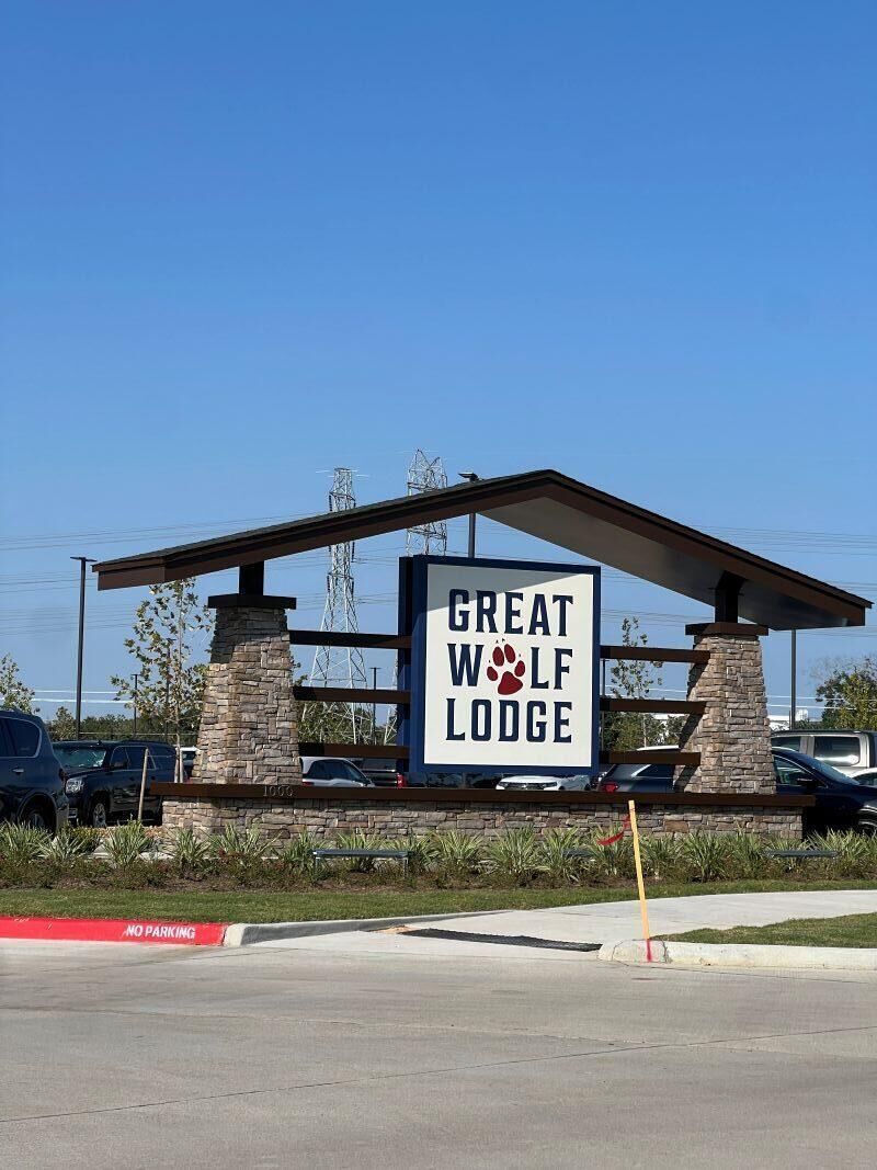 Une enseigne pour le Great Wolf Lodge, dotée d’une architecture moderne, comprenant un pilier en pierre et une structure de toit en métal.