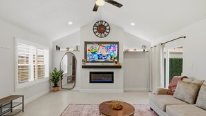 Una sala de estar con chimenea, televisor, ventilador de techo y un espejo grande.