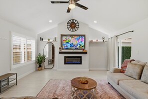 Ein Wohnzimmer mit Kamin, Fernseher, Deckenventilator und einem großen Spiegel.
