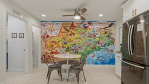 Una cocina con un mural grande en la pared, un refrigerador de acero inoxidable y un ventilador de techo.
