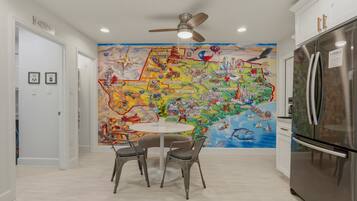 A kitchen with a large wall mural, a stainless steel refrigerator, and a ceiling fan.