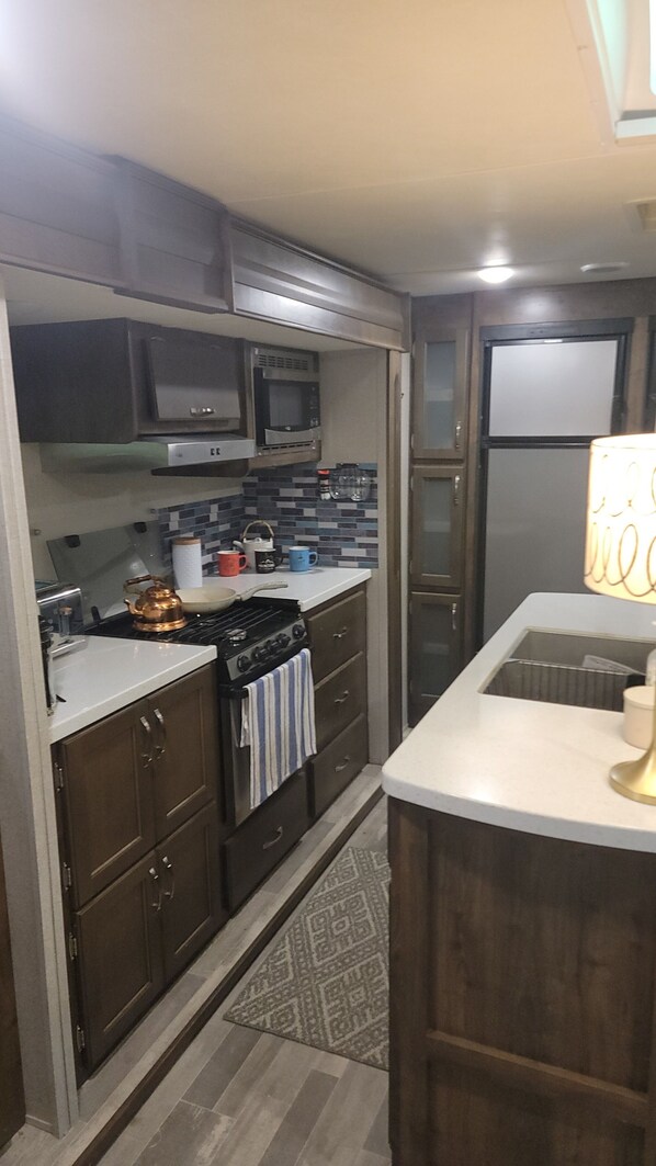 Une cuisine avec des meubles de rangement en bois foncé, une cuisinière, un four à micro-ondes et un réfrigérateur.