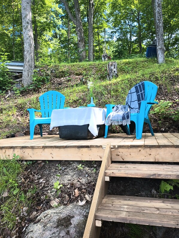 En uteplats med två blå Adirondack-stolar, ett litet bord och en bänk.