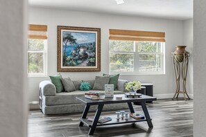 Ein Wohnzimmer mit einer Couch, einem Couchtisch, einem Gemälde und einem Fenster mit Blick.