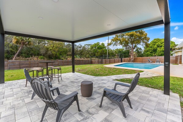 An outdoor patio with a pool, surrounded by a wooden fence and trees. - The Grand Slam House. (Melbourne)