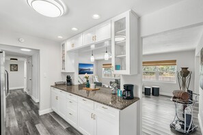 Eine moderne Küche mit weißen Schränken, Granit Arbeitsplatten und Pendelleuchten.