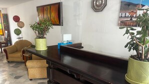En receptionsdisk med en potteplante, et ur og et billede på væggen.
