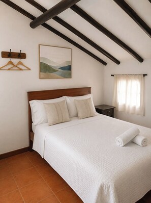 Een slaapkamer met een houten bed, een schilderij aan de muur en een raam met gordijnen.
