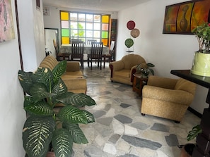 Una sala de estar con piso de piedra, dos sofás, una mesa de centro y un comedor con sillas y una mesa.